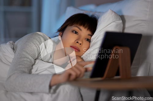 Image of asian woman with tablet pc in bed at home at night