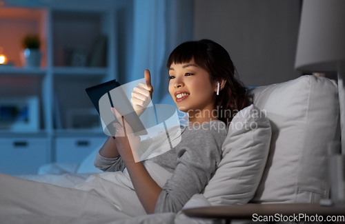 Image of woman with tablet pc in bed has video call at night