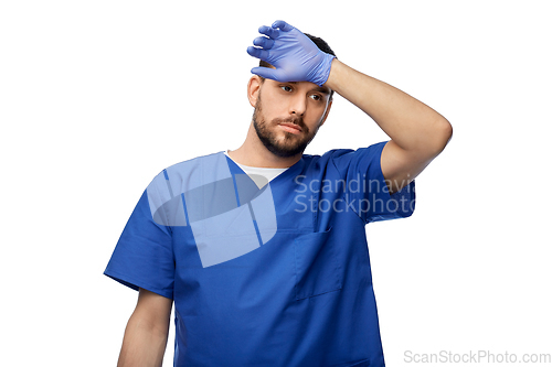 Image of tired doctor or male nurse in blue uniform