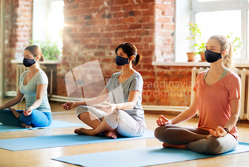 Image of group of women in masks doing yoga at studio