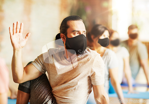 Image of man in mask with group of people doing yoga