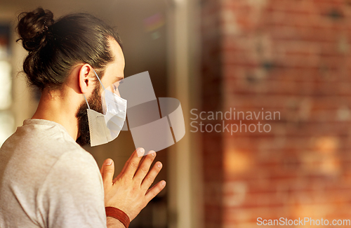 Image of close up of man in mask meditating at yoga studio