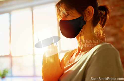 Image of woman in black mask meditating at yoga studio