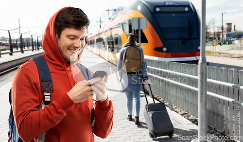 Image of smiling man with smartphone traveling by train