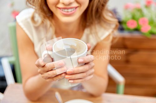 Image of happy young woman drinking coffee at street cafe