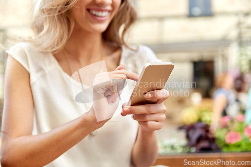 Image of happy woman with smartphone at street cafe