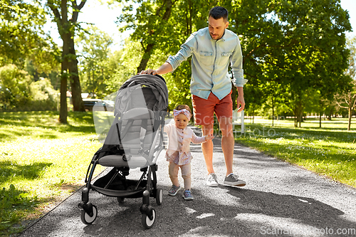 Image of happy father with child in stroller at summer park