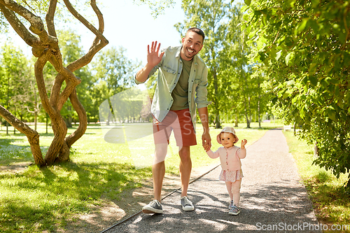 Image of happy father with baby daughter walking at park
