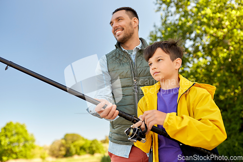 Image of happy smiling father and son fishing on river