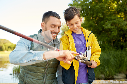 Image of happy smiling father and son fishing on river