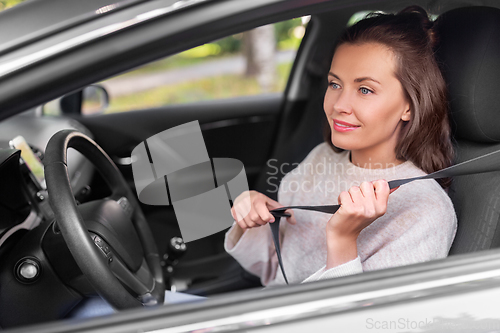 Image of woman or female car driver fastening seat belt