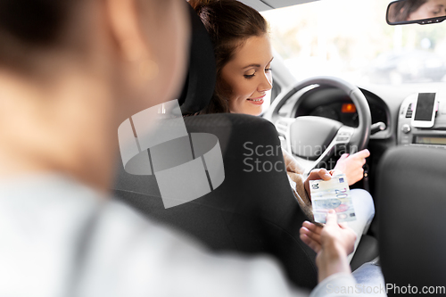 Image of female car driver taking money from passenger