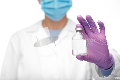 Image of close up of doctor in mask with medicine in bottle