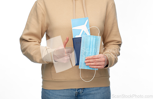 Image of woman with mask, passport and air ticket