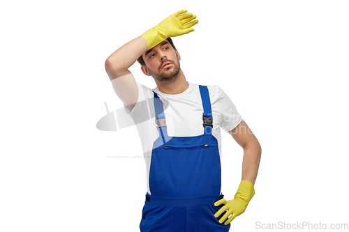 Image of tired male worker or cleaner in overall and gloves