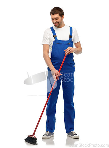 Image of male cleaner in overall cleaning floor with broom