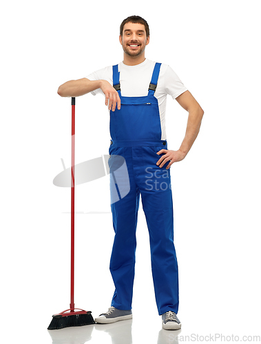 Image of male cleaner in overall cleaning floor with broom