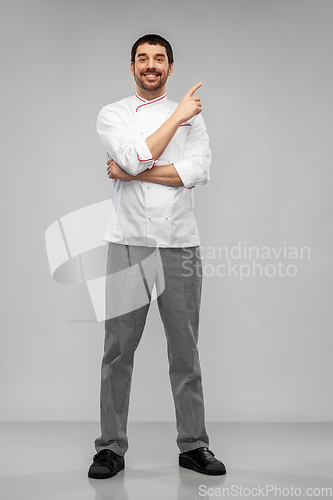 Image of happy smiling male chef pointing to something