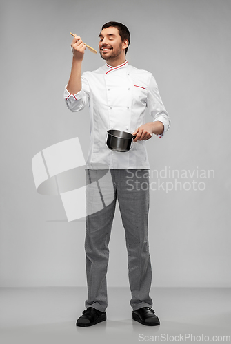 Image of happy smiling male chef with saucepan tasting food