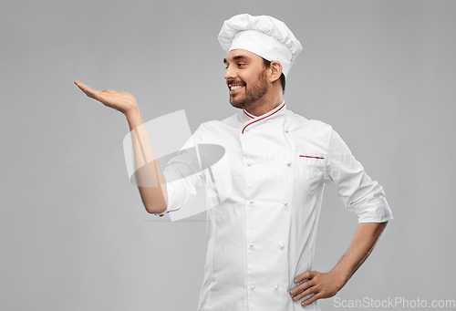 Image of happy smiling male chef holding something on hand