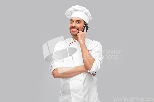 Image of happy smiling male chef calling on smartphone