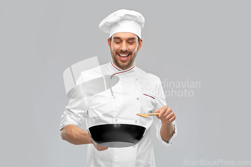 Image of smiling male chef with frying pan cooking food