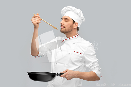 Image of happy male chef with frying pan tasting food