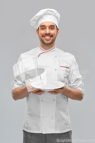 Image of happy smiling male chef holding empty plate