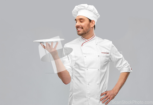 Image of happy smiling male chef holding empty plate