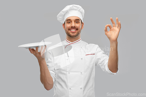 Image of happy smiling male chef holding empty plate