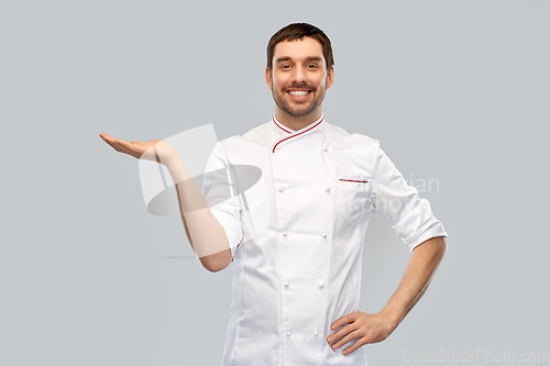 Image of happy smiling male chef holding something on hand