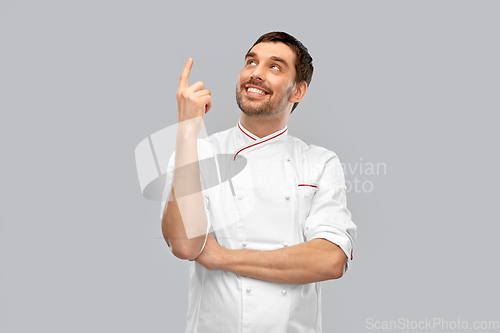 Image of happy smiling male chef pointing finger up