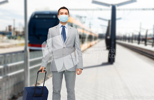 Image of businessman in mask with travel bag over train