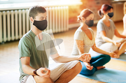 Image of group of people in masks doing yoga at studio