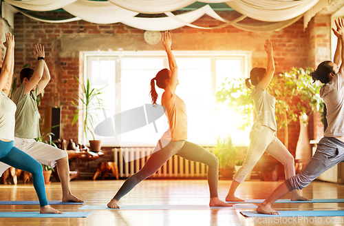 Image of group of people doing yoga warrior pose at studio