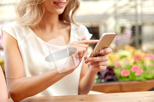 Image of happy woman with smartphone at street cafe