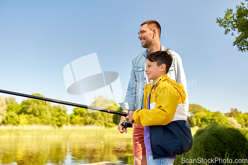 Image of happy smiling father and son fishing on river