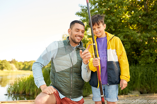 Image of happy smiling father and son fishing on river