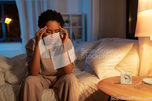 Image of stressed african woman lying in bed at night