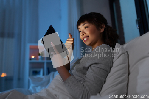 Image of woman with tablet pc in bed has video call at night