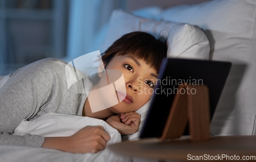 Image of asian woman with tablet pc in bed at home at night