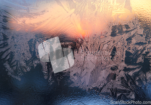 Image of Ice patterns, water drops and sunlight on a window glass