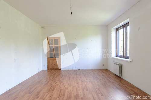 Image of Fragment of a room with a fine finish, view of the front door, there is one window in the room