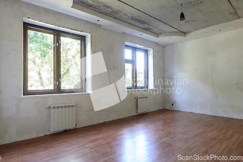 Image of The interior of an empty room during renovation, there are two large windows in the room, heating radiators are located under the windows