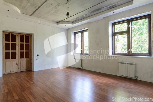 Image of Interior of an empty room during renovation, view of a wall with windows and a wall with a door