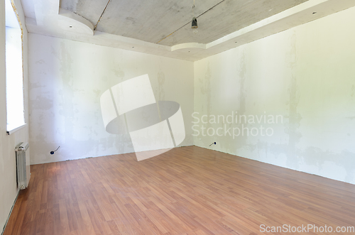 Image of Interior of an empty room during renovation with plastered walls and laminate flooring