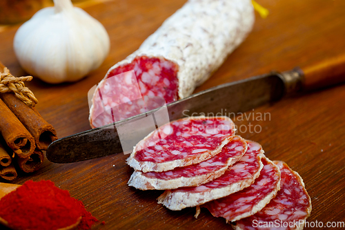 Image of traditional Italian salame cured sausage sliced on a wood board