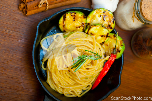 Image of italian spaghetti pasta with zucchini sauce on iron skillet