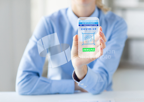 Image of hand with certificate of vaccination on smartphone