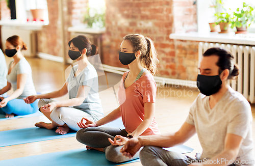 Image of group of people in masks doing yoga at studio